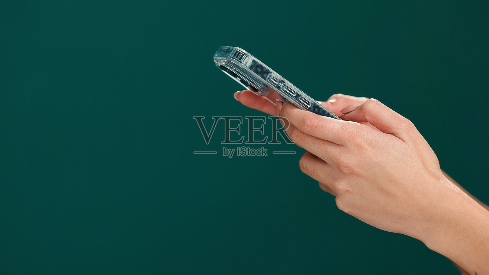 模拟空间,女性的手与手机在工作室中,涉及网络、沟通或社交媒体。科技、联系和使用手机的人,适用于在线、移动应用或发短信,背景为绿色。照片摄影图片