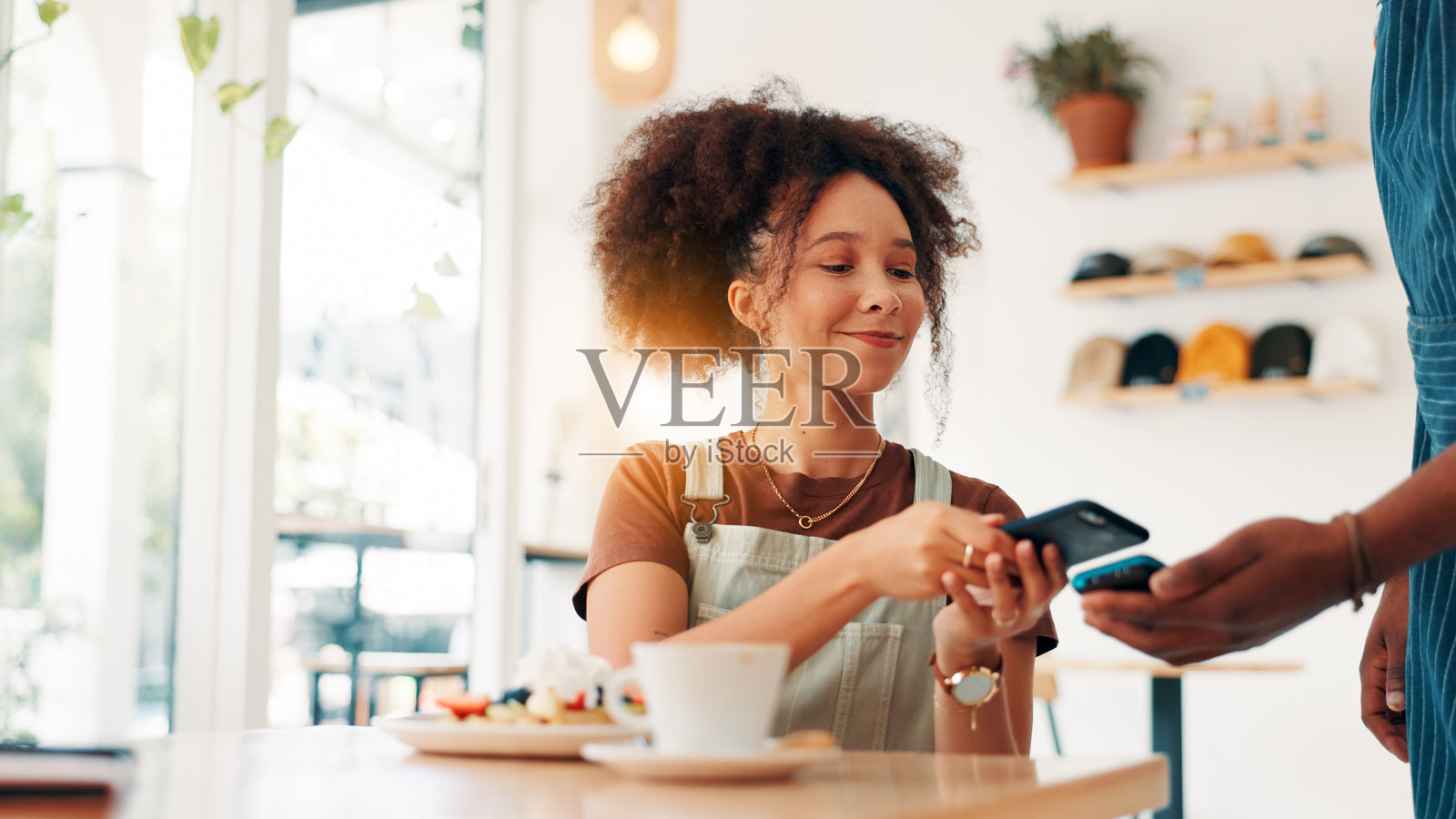 咖啡店,带有卡机的女性在咖啡馆中为顾客提供服务,进行在线交易、支付和购买早餐华夫饼。照片摄影图片