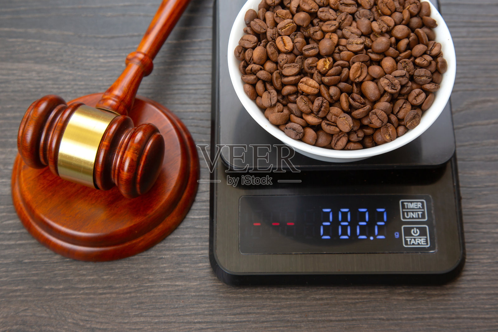 一把带金环的木槌旁边放着一个显示282.2克的电子秤,上面放着一碗烘焙咖啡豆,背景是深色木质表面,适合咖啡法律或正义主题。照片摄影图片