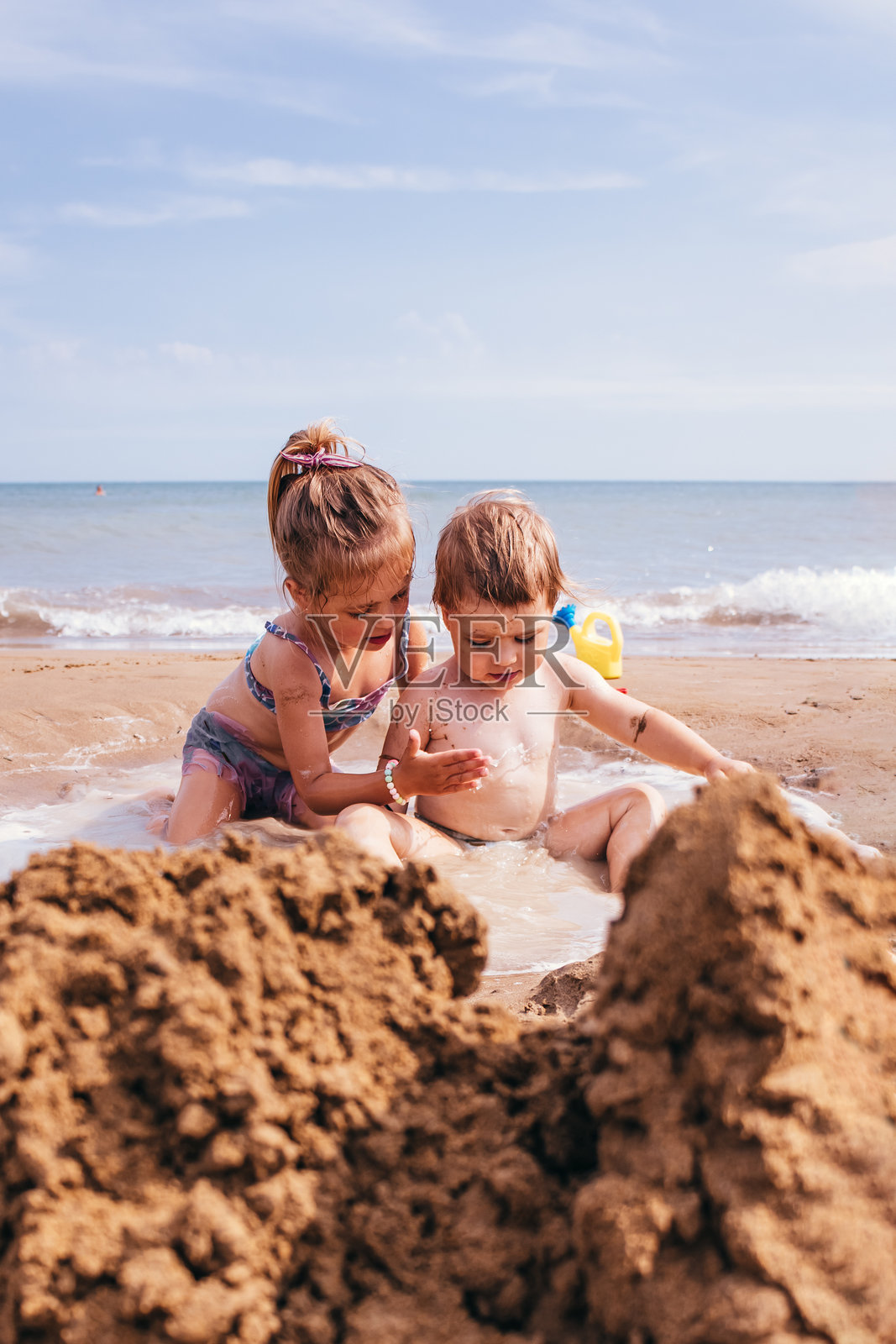 两个女孩在海边堆沙堡照片摄影图片