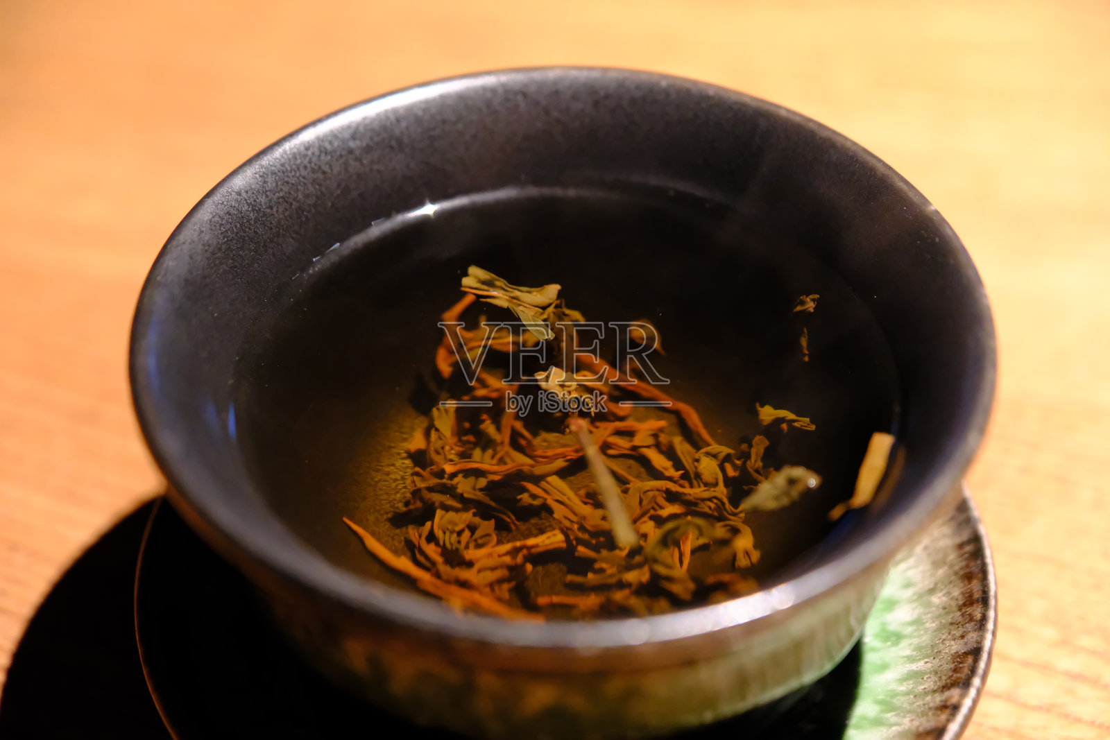 茶叶浸泡在黑茶碗中照片摄影图片