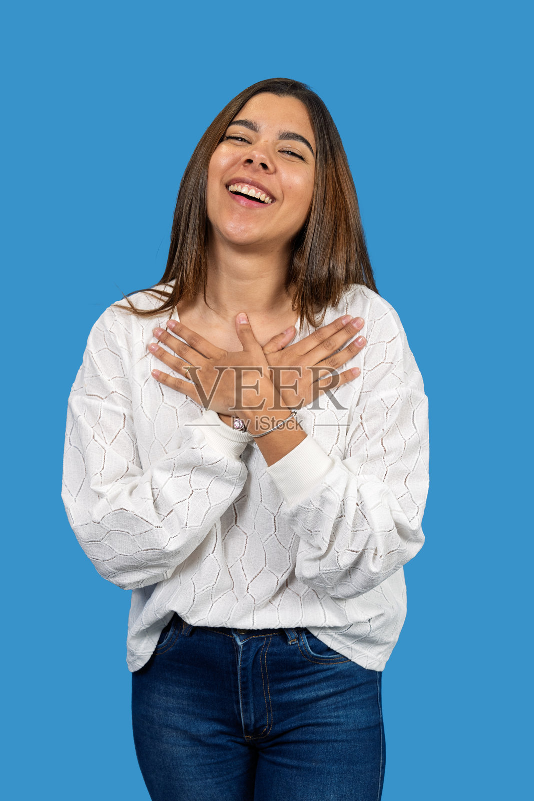 年轻的拉丁裔女性双手放在胸前,表达感激和快乐。照片摄影图片