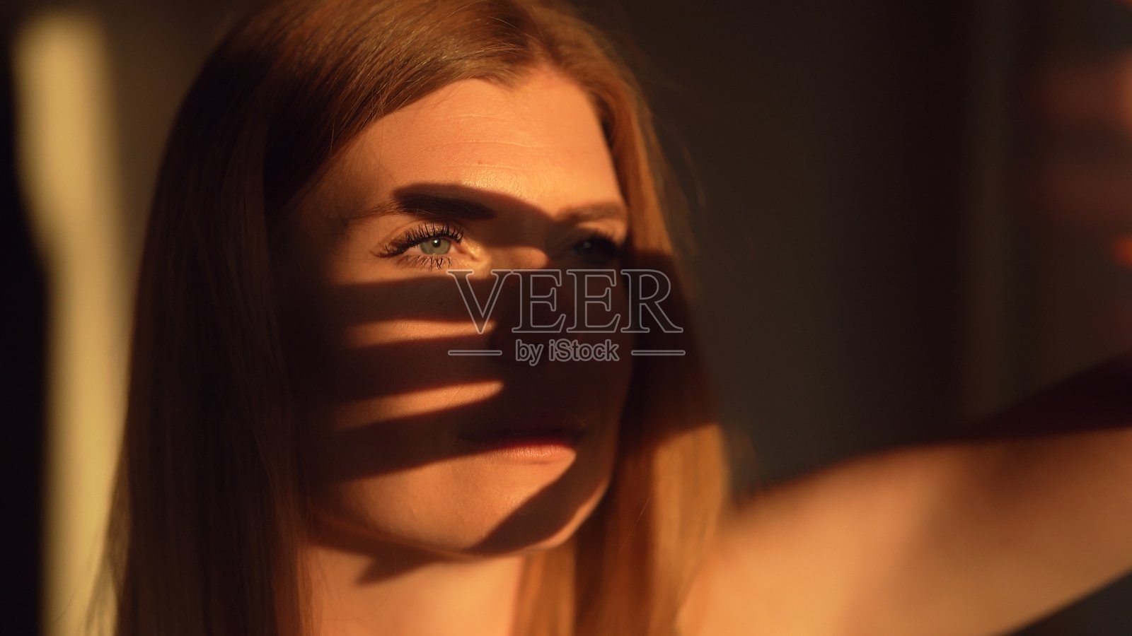 一位女性用手遮住脸以避开阳光。照片摄影图片