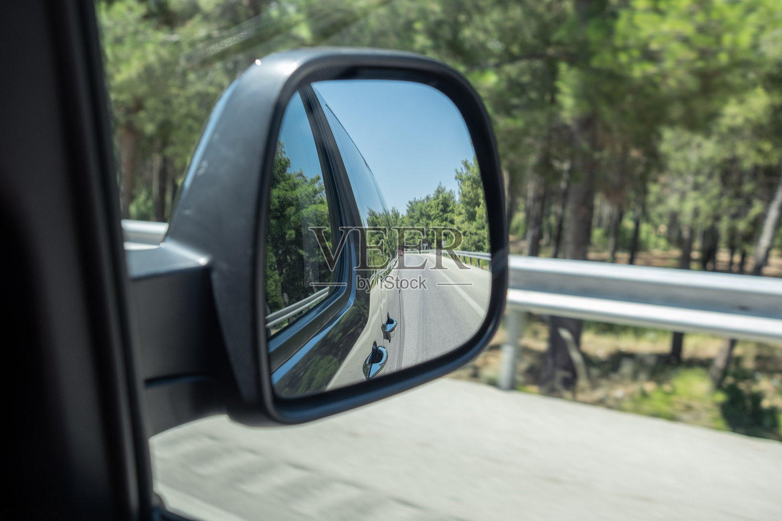 阳光明媚的森林中,车侧镜中映出的蜿蜒道路的倒影照片摄影图片