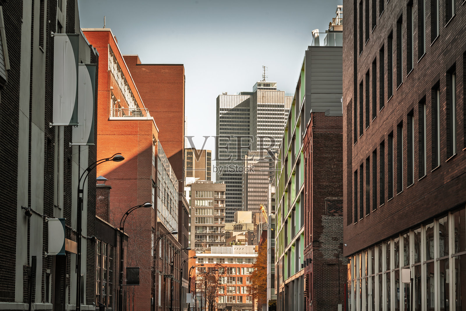 蒙特利尔市中心的商务摩天大楼,从一条狭窄的侧街看到。砖砌的中层建筑引导视线到现代办公大楼,这些大楼代表了加拿大魁北克省城市的企业和金融核心。照片摄影图片