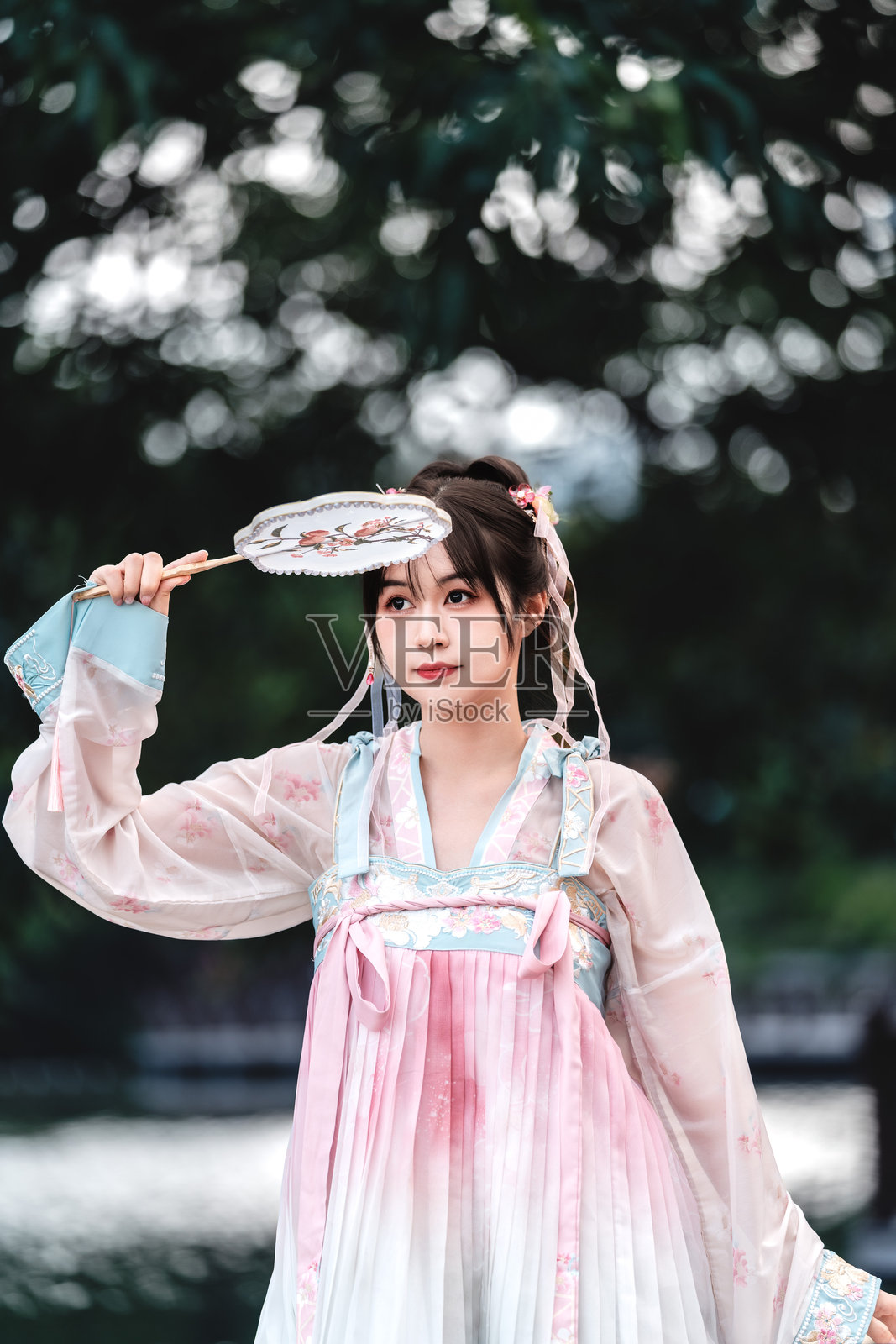 美丽的亚洲女性穿着汉服,在传统中国园林中手持扇子。照片摄影图片