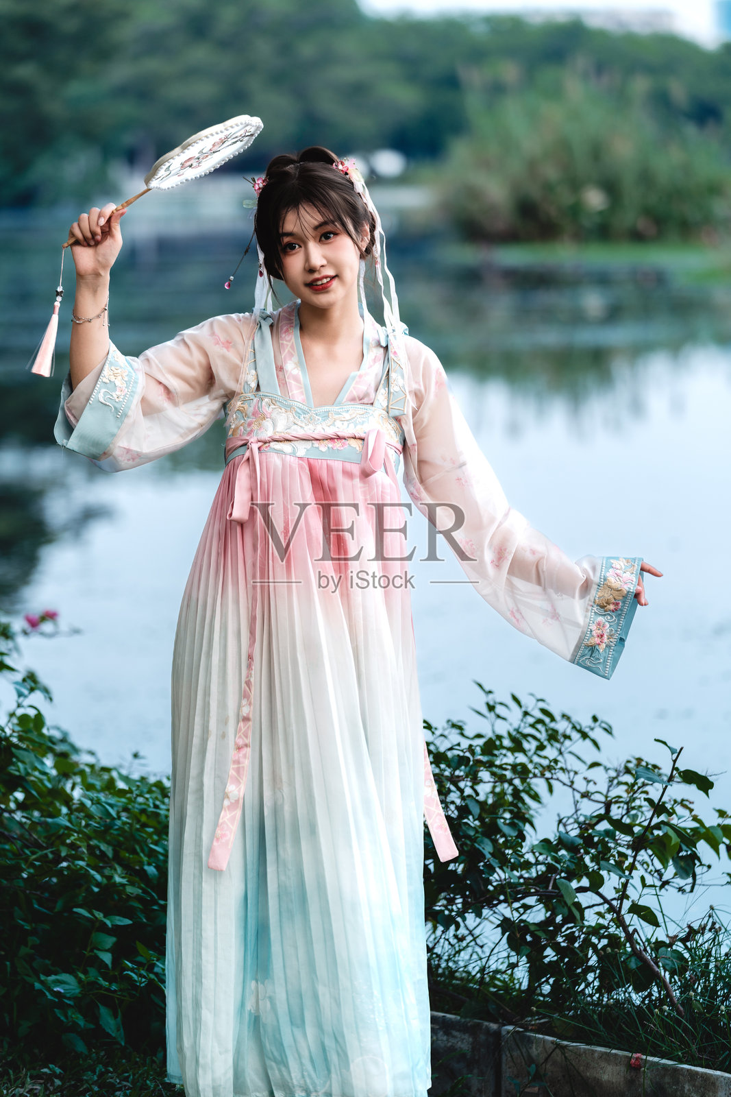 美丽的亚洲女性穿着汉服,在传统中国园林的湖边欣赏自然之美。照片摄影图片