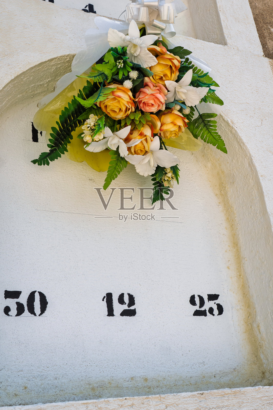 一段苦乐参半的圣诞回忆:墓碑上的花朵标记着12月25日。照片摄影图片