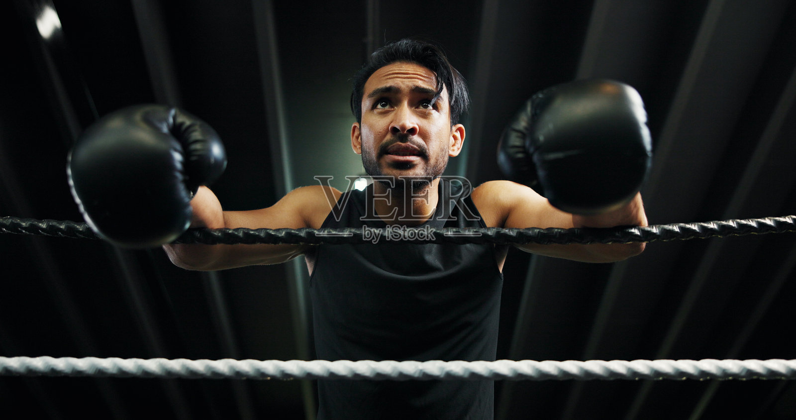 运动员、拳击手和绳索上的休息,疲惫或健康恢复以保持体能。拳击台上的运动员在健身房休息,因激烈的挑战而感到疲惫、出汗或精疲力竭。照片摄影图片