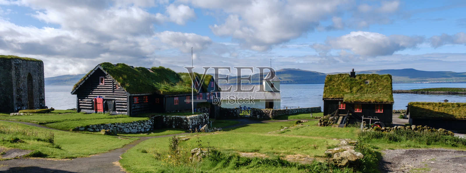 法罗群岛风景如画的海滨村庄,被郁郁葱葱的绿意和宁静的水域环绕照片摄影图片