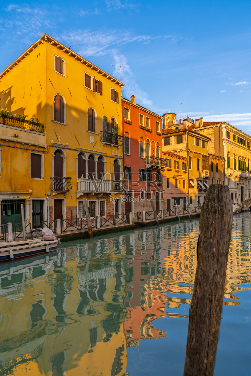 狭窄的威尼斯运河,色彩斑斓的历史建筑和贡多拉照片摄影图片