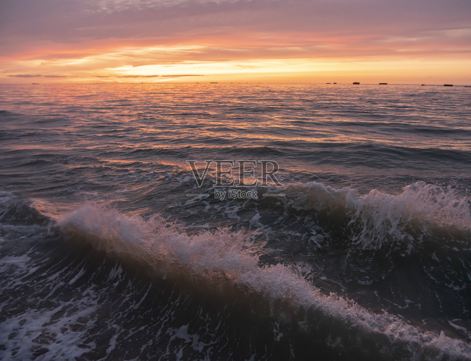 法国阿斯内尔-苏尔-梅尔 - 2025年8月8日:日落时分,码头沿线的海洋、波浪和多彩的云朵全景。照片摄影图片