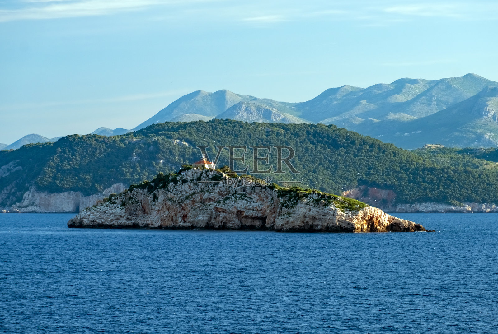 克罗地亚达尔马提亚日出时的杜布罗夫尼克群岛、灯塔和远处的山脉,海上视角照片摄影图片