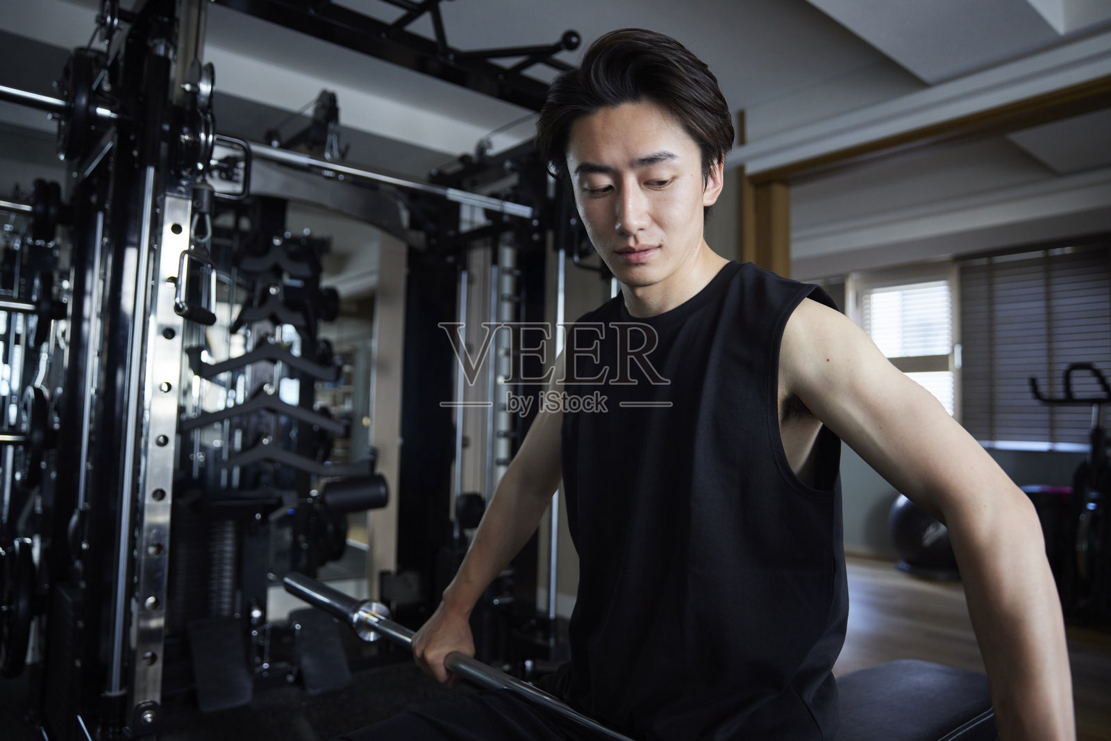 年轻的日本男子穿着运动服在健身房进行力量训练照片摄影图片