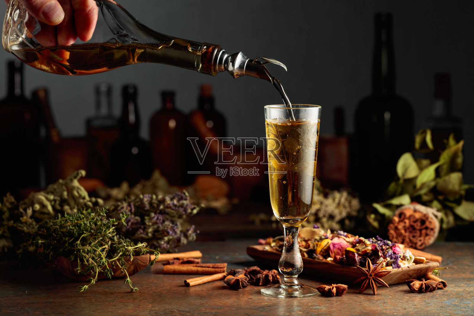 黄色草药酒或混合饮料从一瓶复古瓶中倒入玻璃杯。照片摄影图片