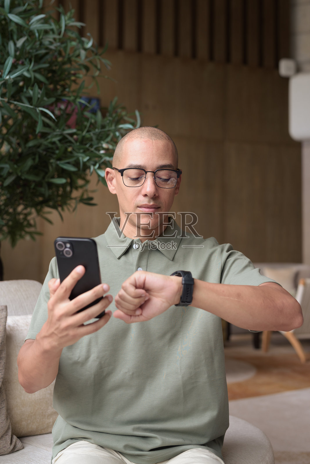 在酒店休息室咖啡馆中使用智能手机的西班牙裔秃头男士,展现休闲生活方式和交流。照片摄影图片