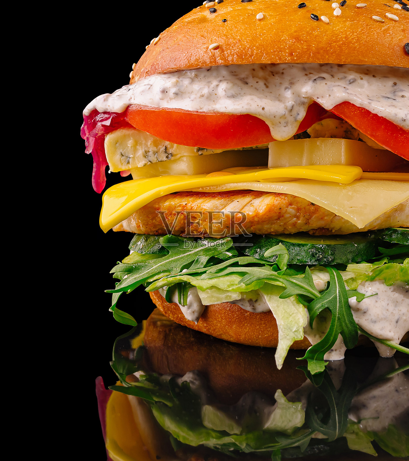 美味的汉堡配新鲜蔬菜和奶油酱,背景为深色。照片摄影图片