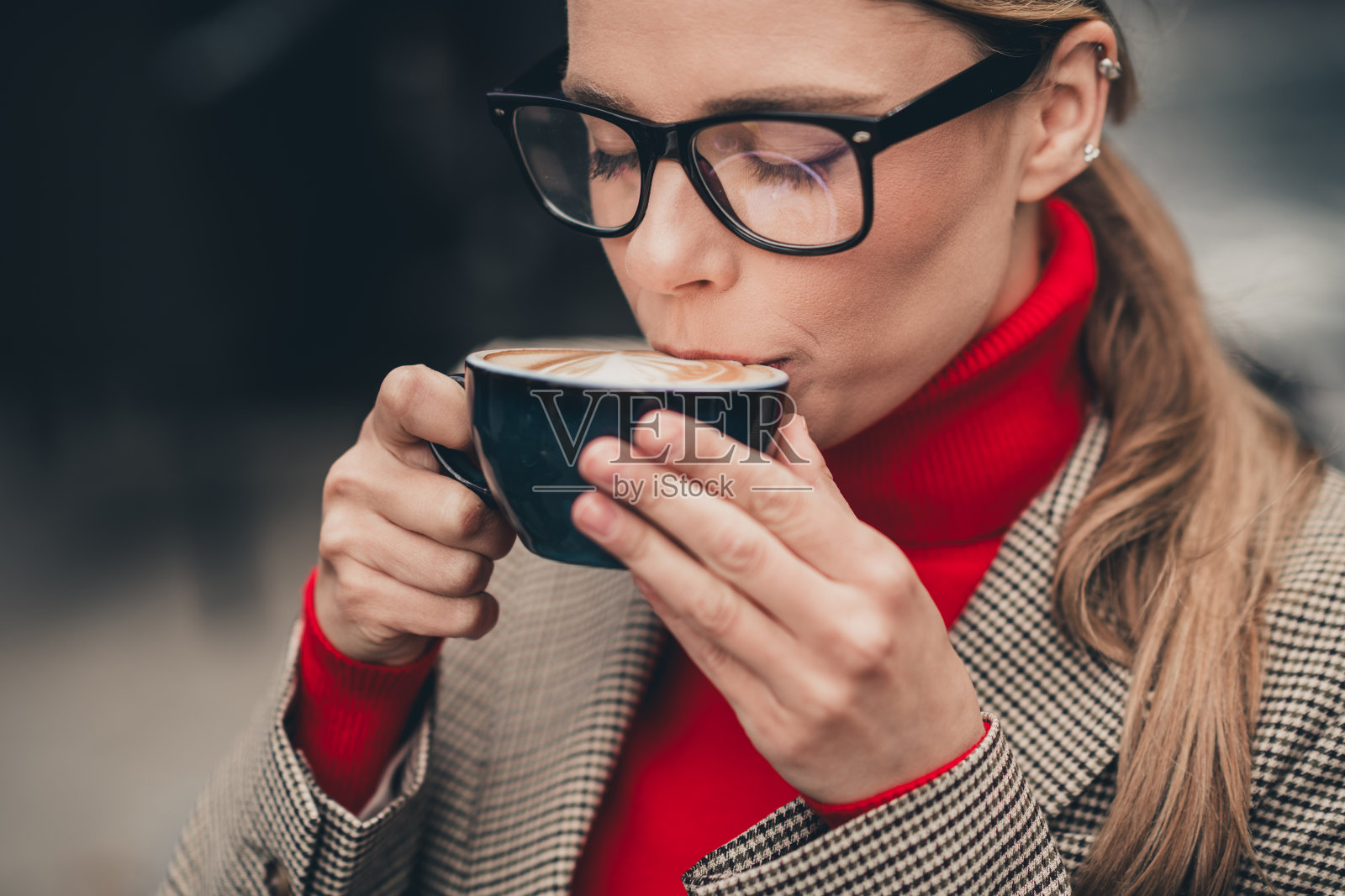 迷人的女性在安静的城市早晨优雅地穿着商务服装,享受户外咖啡时光。照片摄影图片