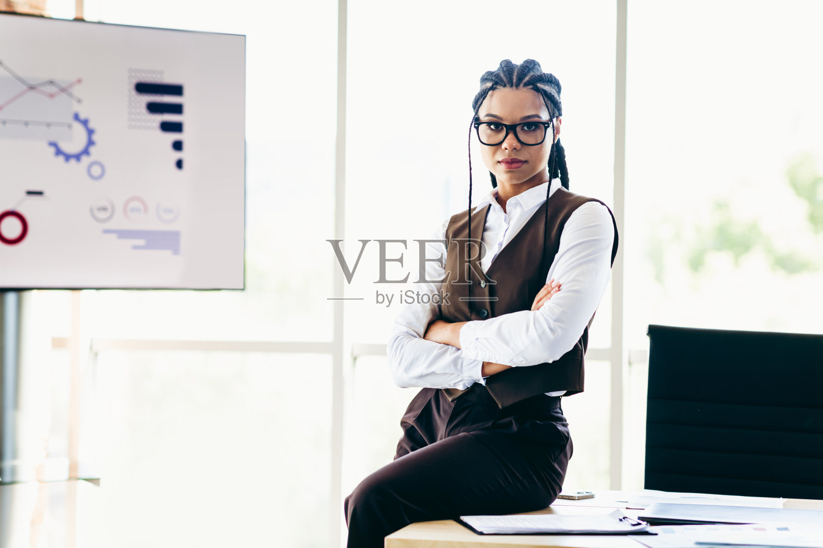 自信的女商人在现代办公室环境中站立,展示成功的职业领导能力和图表。照片摄影图片