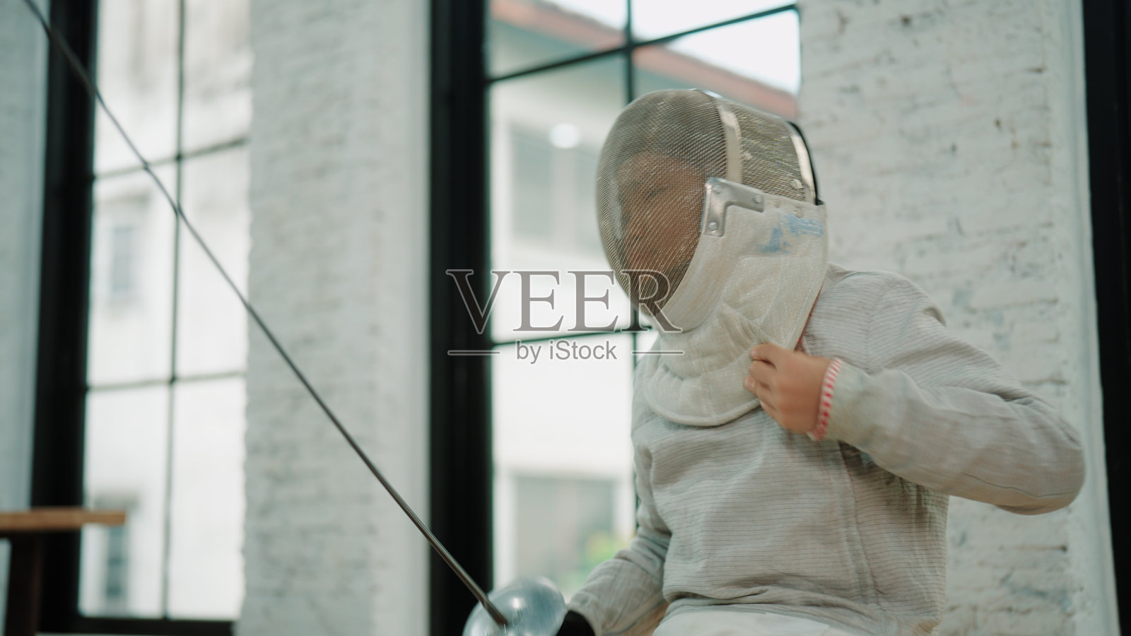 年轻的击剑手正在戴上手套和面具,为比赛做准备照片摄影图片