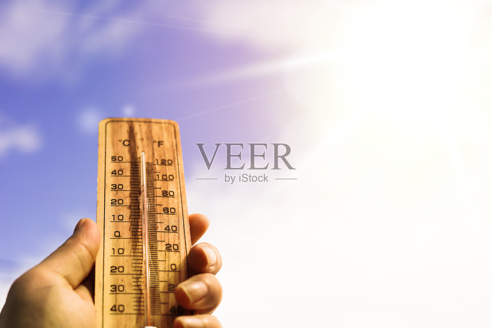 一只手握着一个木制温度计。照片摄影图片