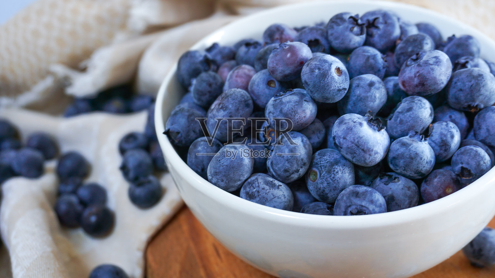 新鲜蓝莓放在木质砧板上的白色碗中照片摄影图片