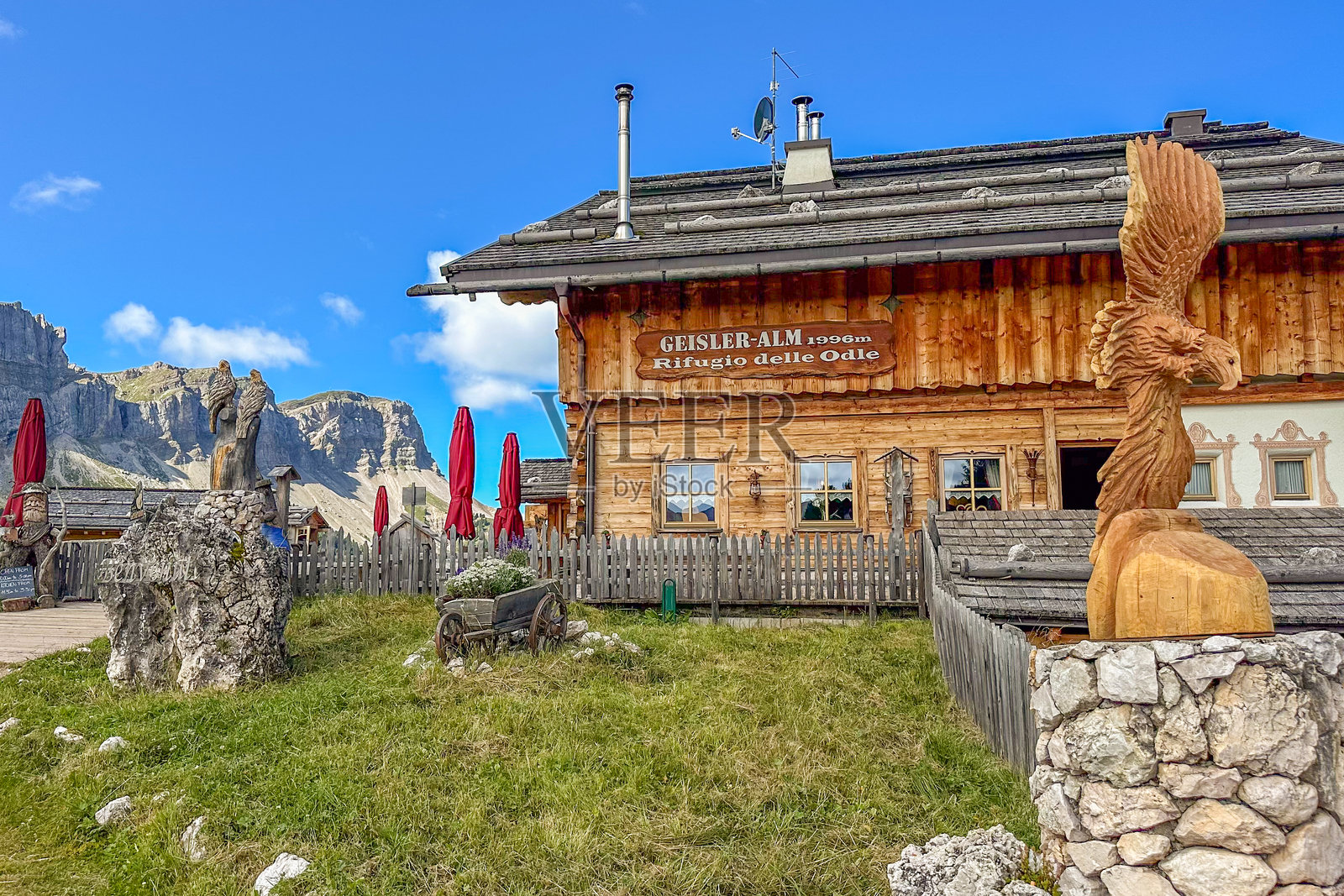 雕刻鹰雕像的木质阿尔卑斯小屋Geisler Alm,背景是多洛米蒂山峰照片摄影图片