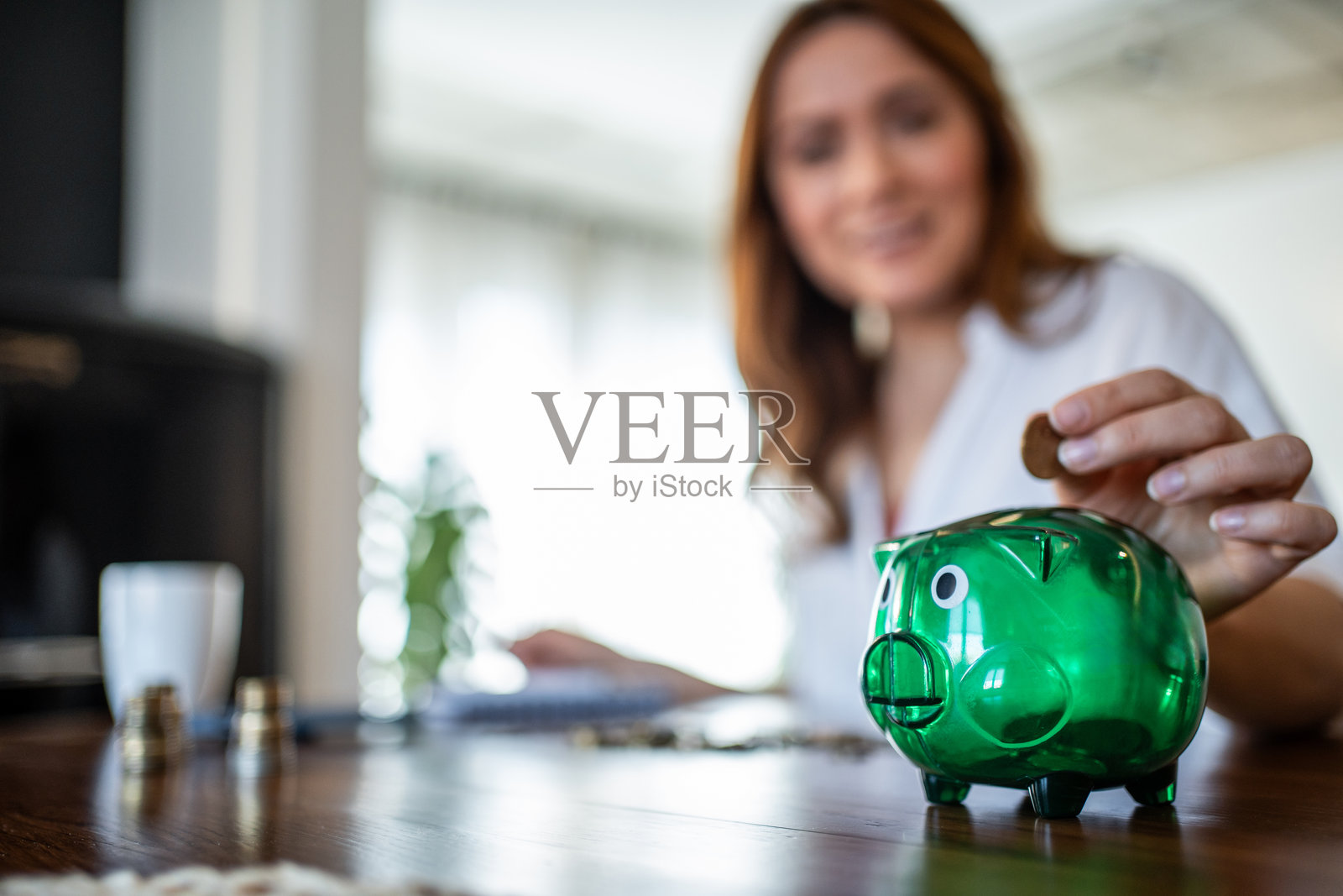 女人将硬币放入储蓄罐中存钱照片摄影图片