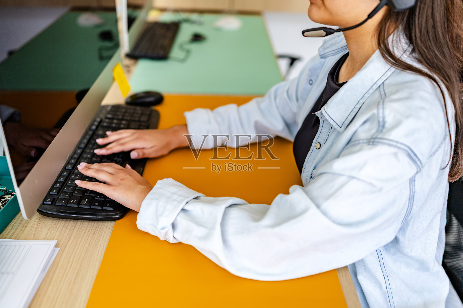 年轻女性在现代家居环境中使用耳机并在键盘上打字,坐在桌子前工作照片摄影图片