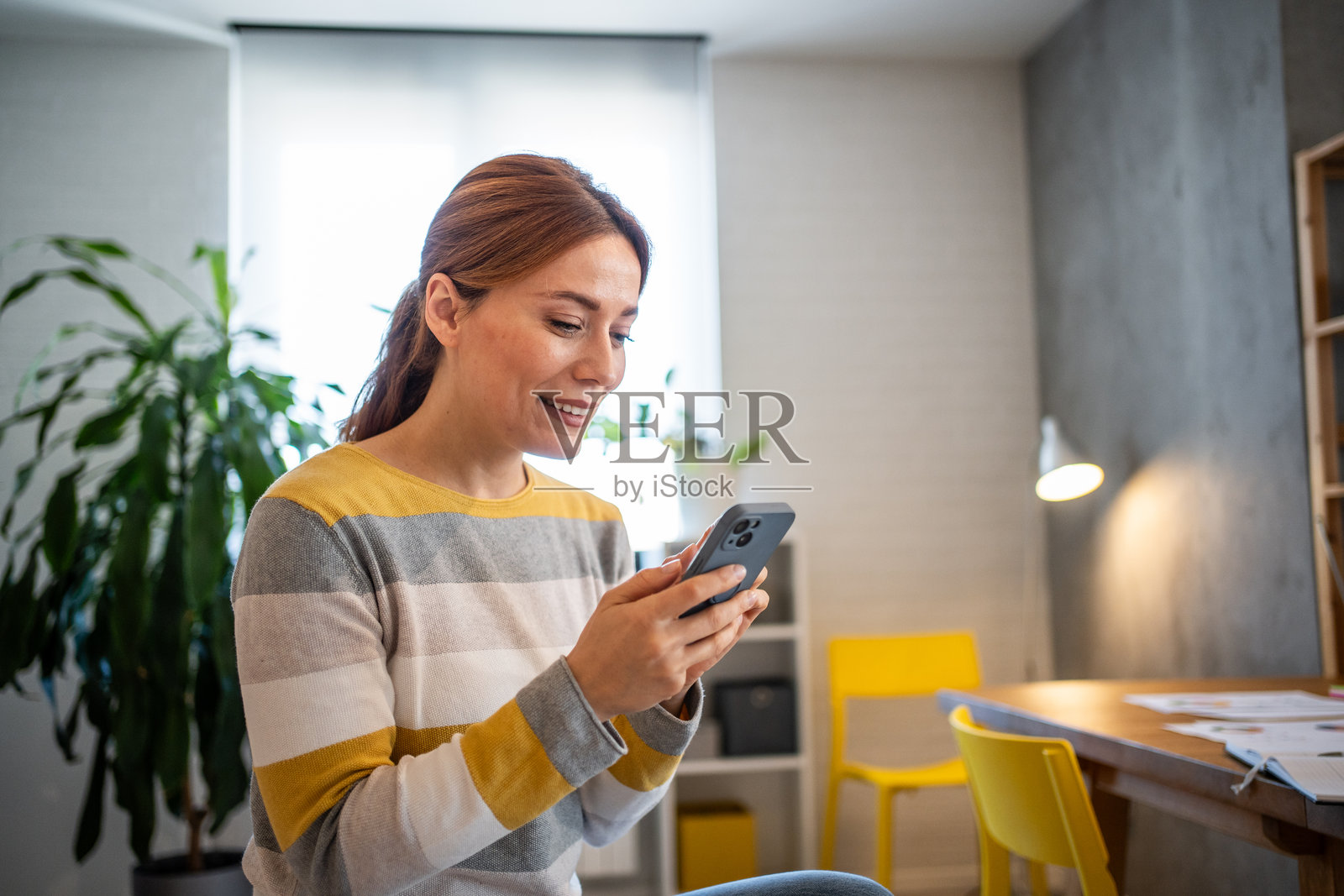 微笑的女性在家中办公室使用智能手机照片摄影图片