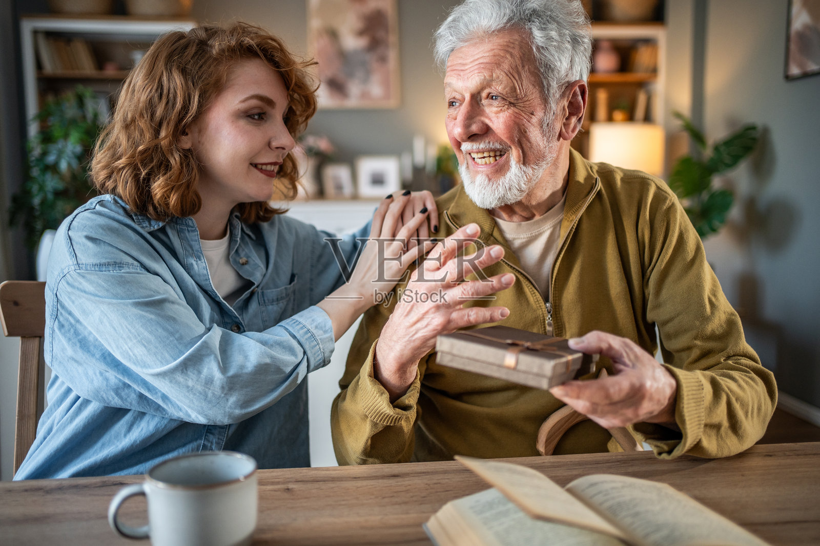 年轻女性在家中给祖父送礼物照片摄影图片