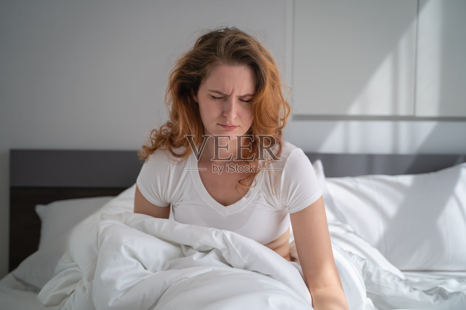 一位年轻女性 感到困倦和不适,不想在早晨醒来。照片摄影图片