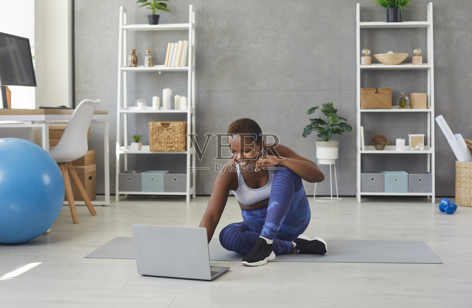 年轻的非裔美国女性在家中运动时打开笔记本电脑上的视频。照片摄影图片