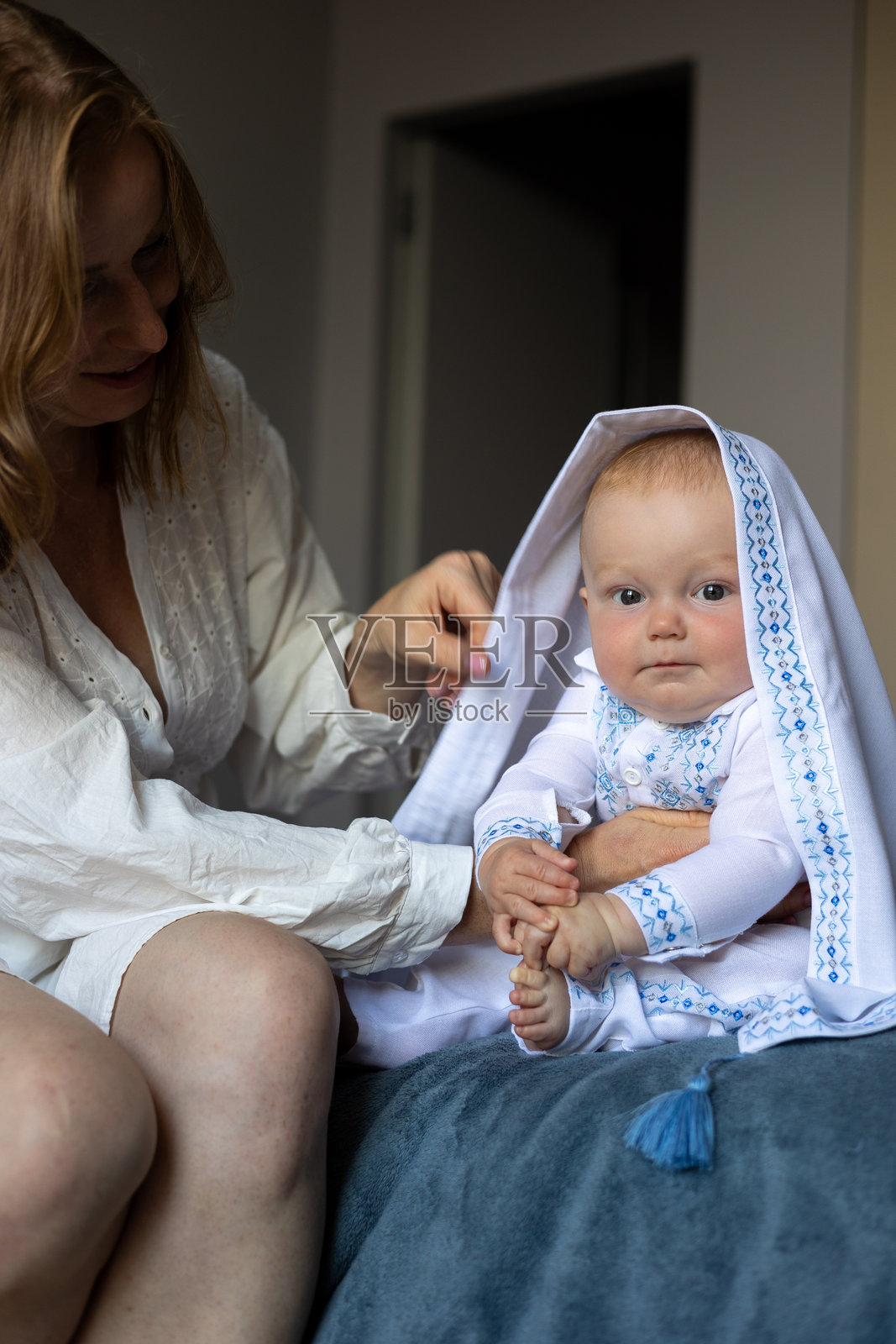 穿着刺绣白色服装的婴儿与母亲在家中照片摄影图片
