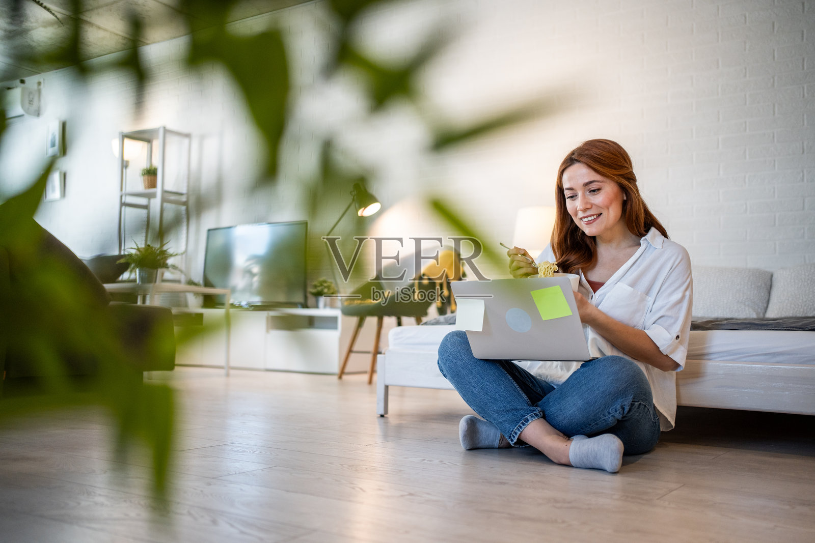 年轻女性在家远程工作并吃沙拉照片摄影图片