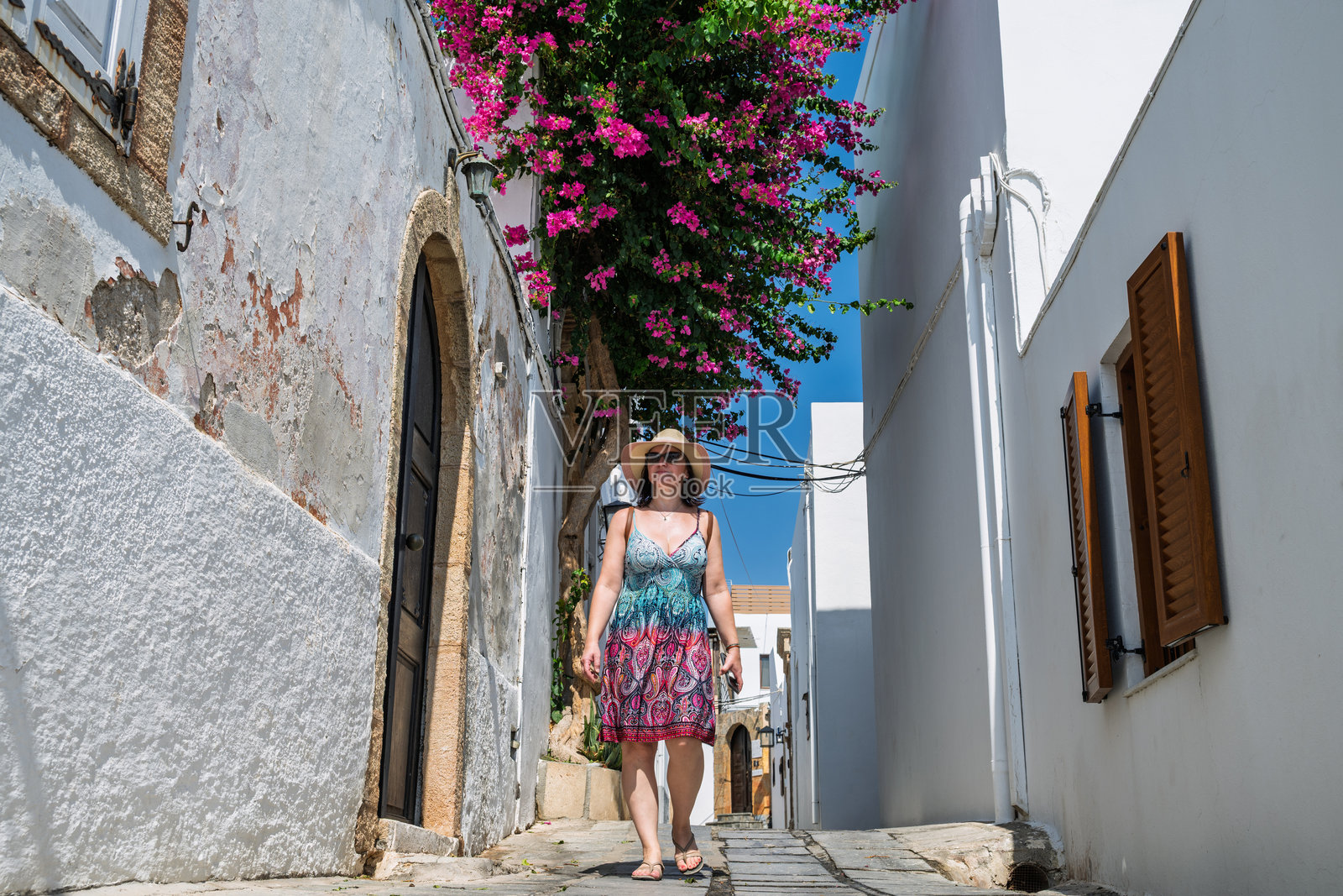 女人在卡尔帕索斯的古老村庄街道上探险照片摄影图片