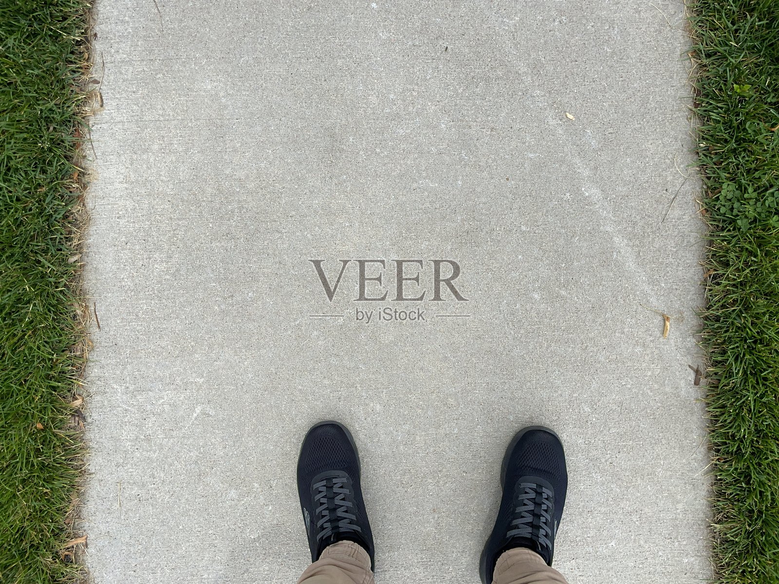 一个人站在绿草之间的混凝土小路上照片摄影图片