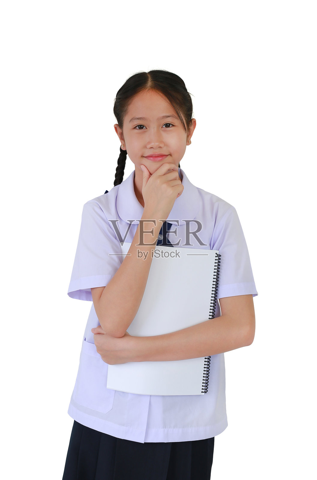 身穿校服的亚洲学生女孩,手托下巴,想象着心中的某个画面,同时手中拿着一本书,背景为白色。照片摄影图片