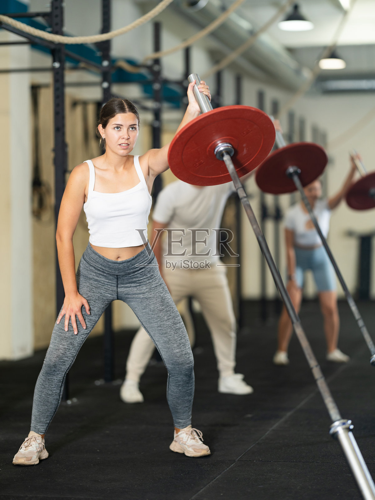 年轻的运动女性用一只手举哑铃锻炼手臂肌肉照片摄影图片
