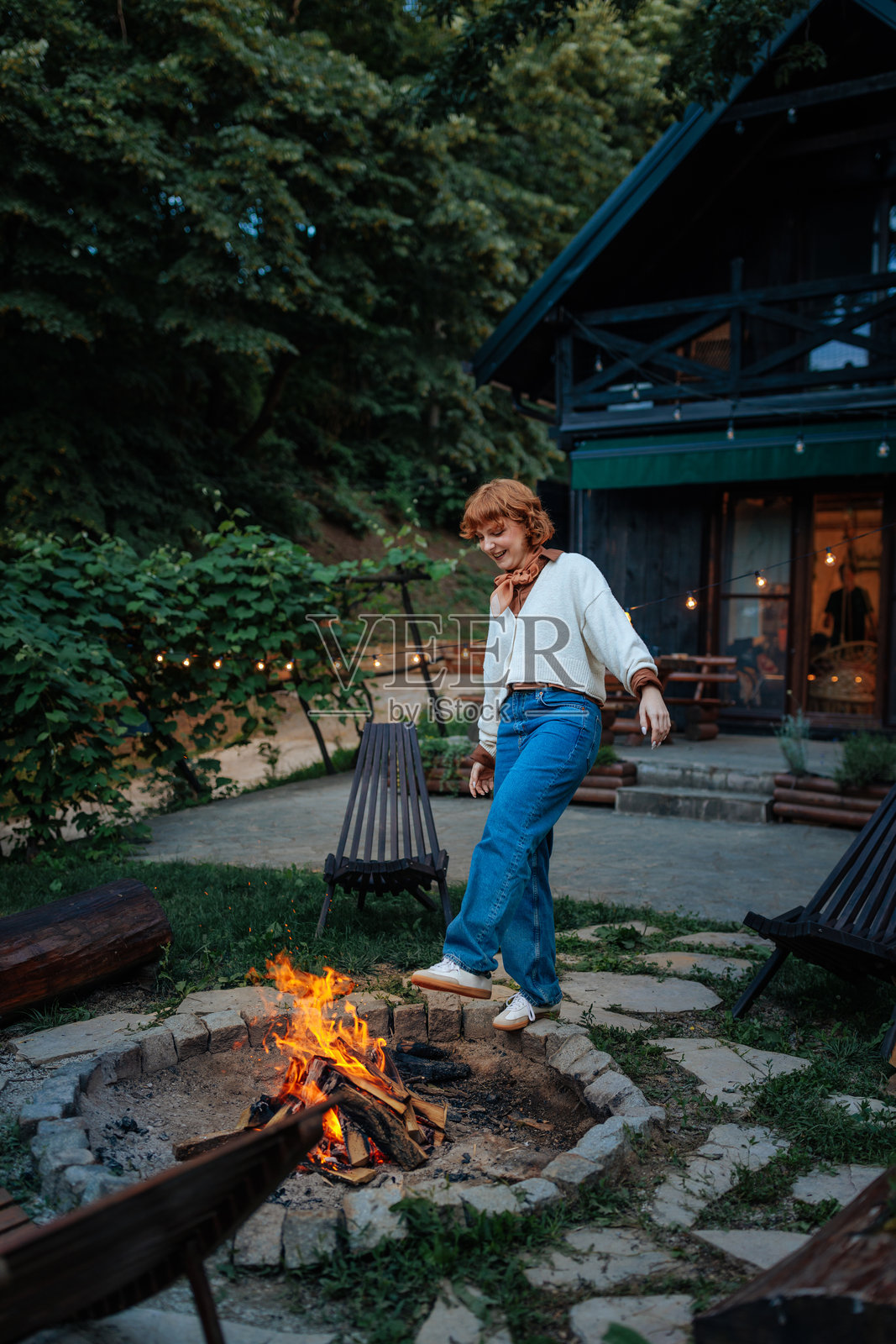 女人在后院的篝火旁取暖。照片摄影图片