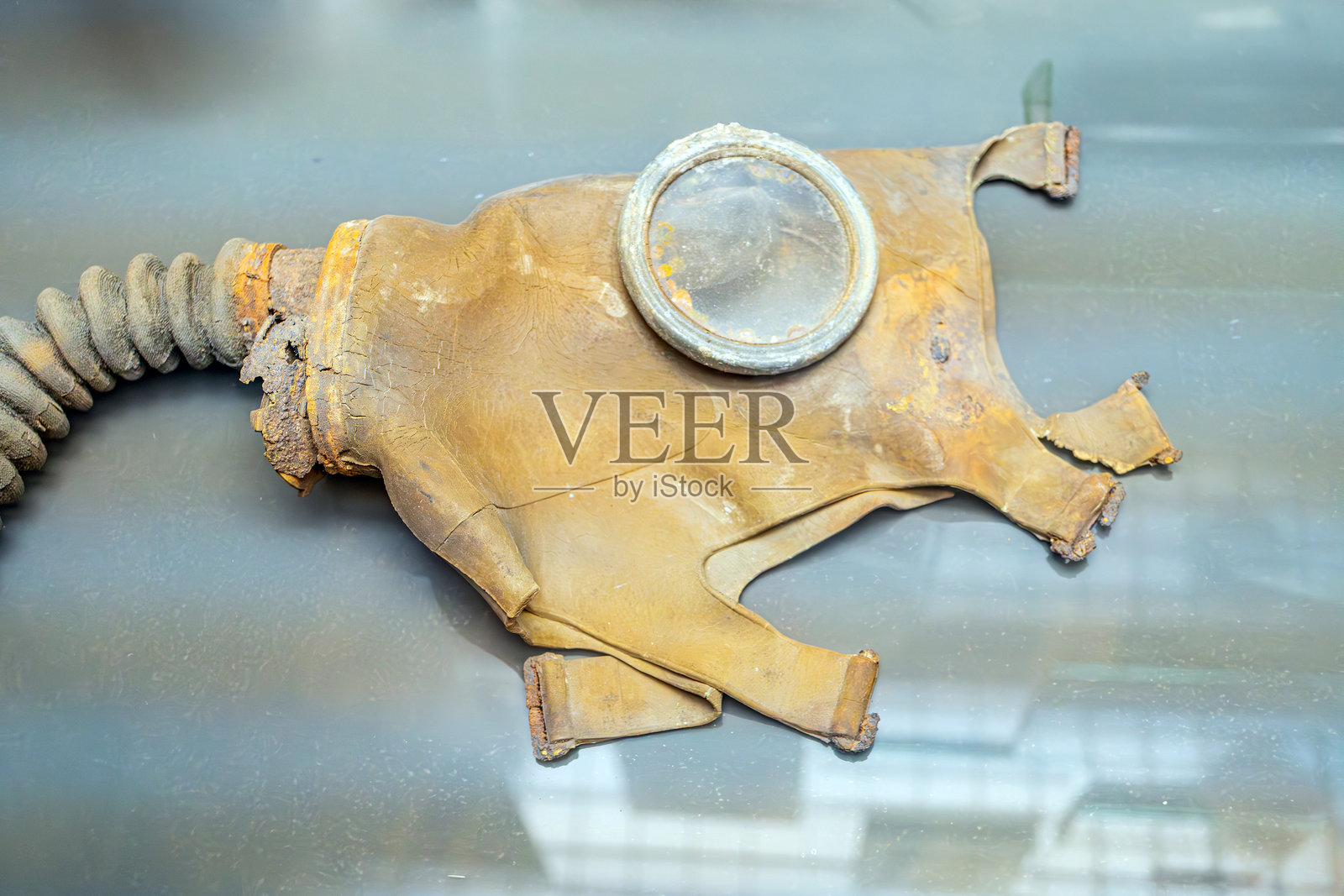 复古金属潜水头盔,带有延长的嘴管,表面布满锈迹,展示在明亮的表面上,背景为深色,置于博物馆或展览环境中照片摄影图片