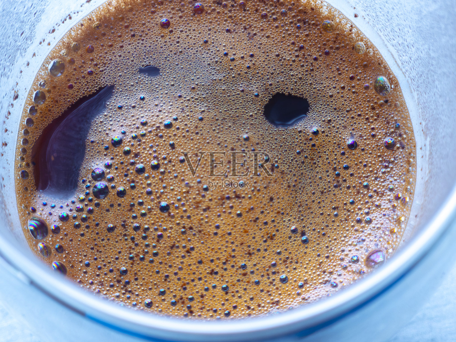 新鲜冲泡的咖啡特写,杯中泡沫形成抽象图案照片摄影图片