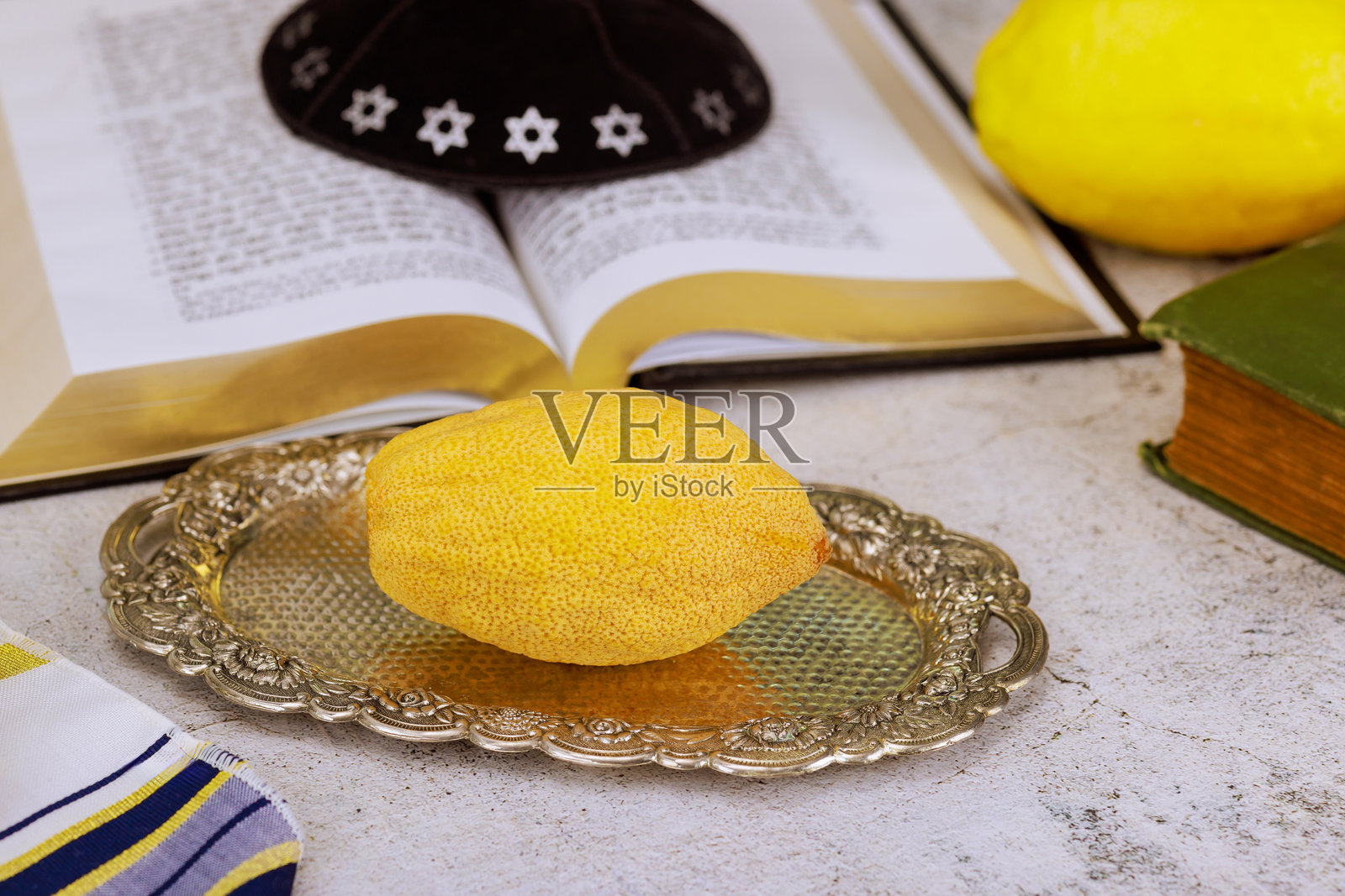 犹太教住棚节的节日传统。银盘上的艾特罗果与祷告书和基帕。照片摄影图片