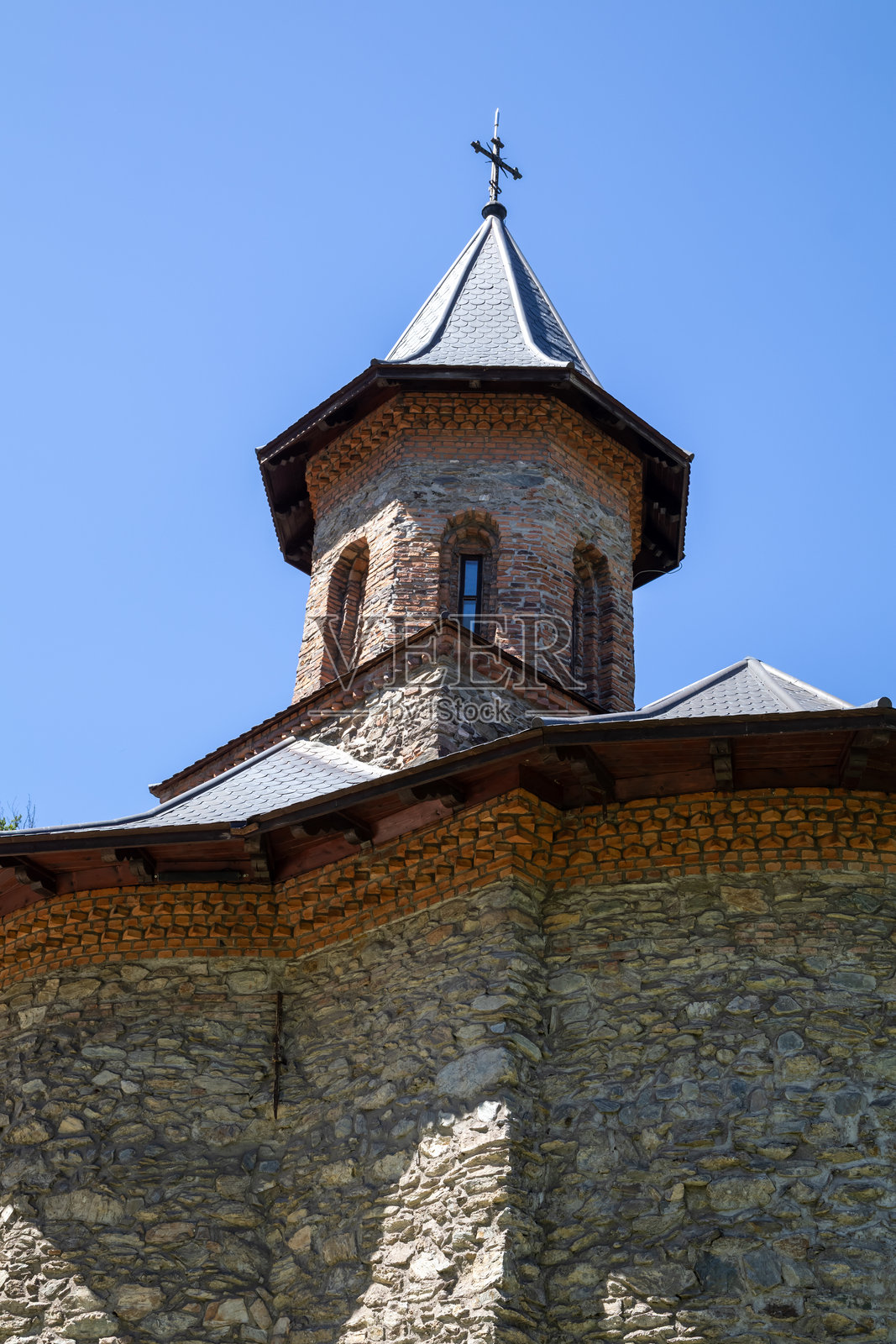 罗马尼亚历史悠久的普里斯洛普修道院的低角度视图,著名的朝圣地,具有石塔和灰色屋顶。照片摄影图片