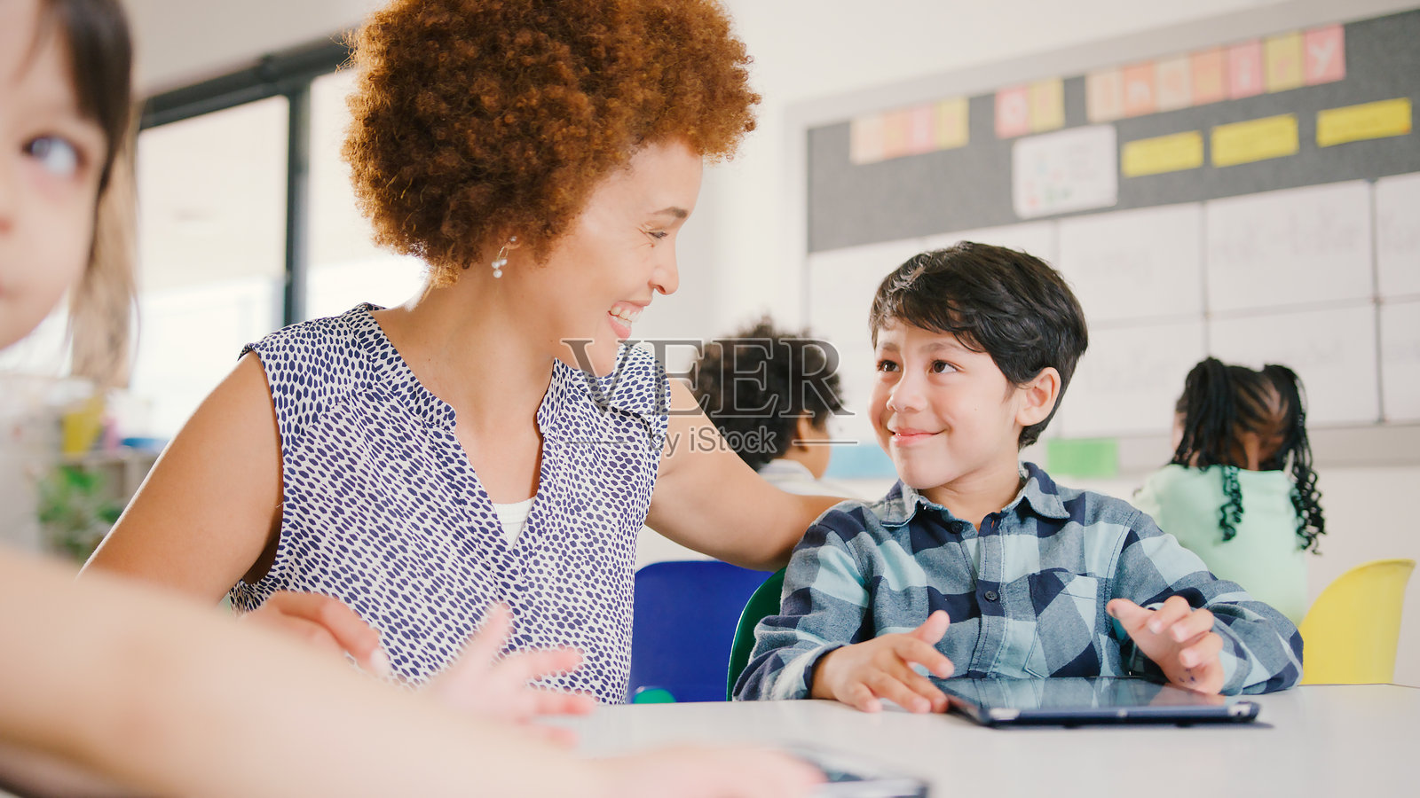 女教师与多元文化的小学生在学校使用数字平板电脑照片摄影图片