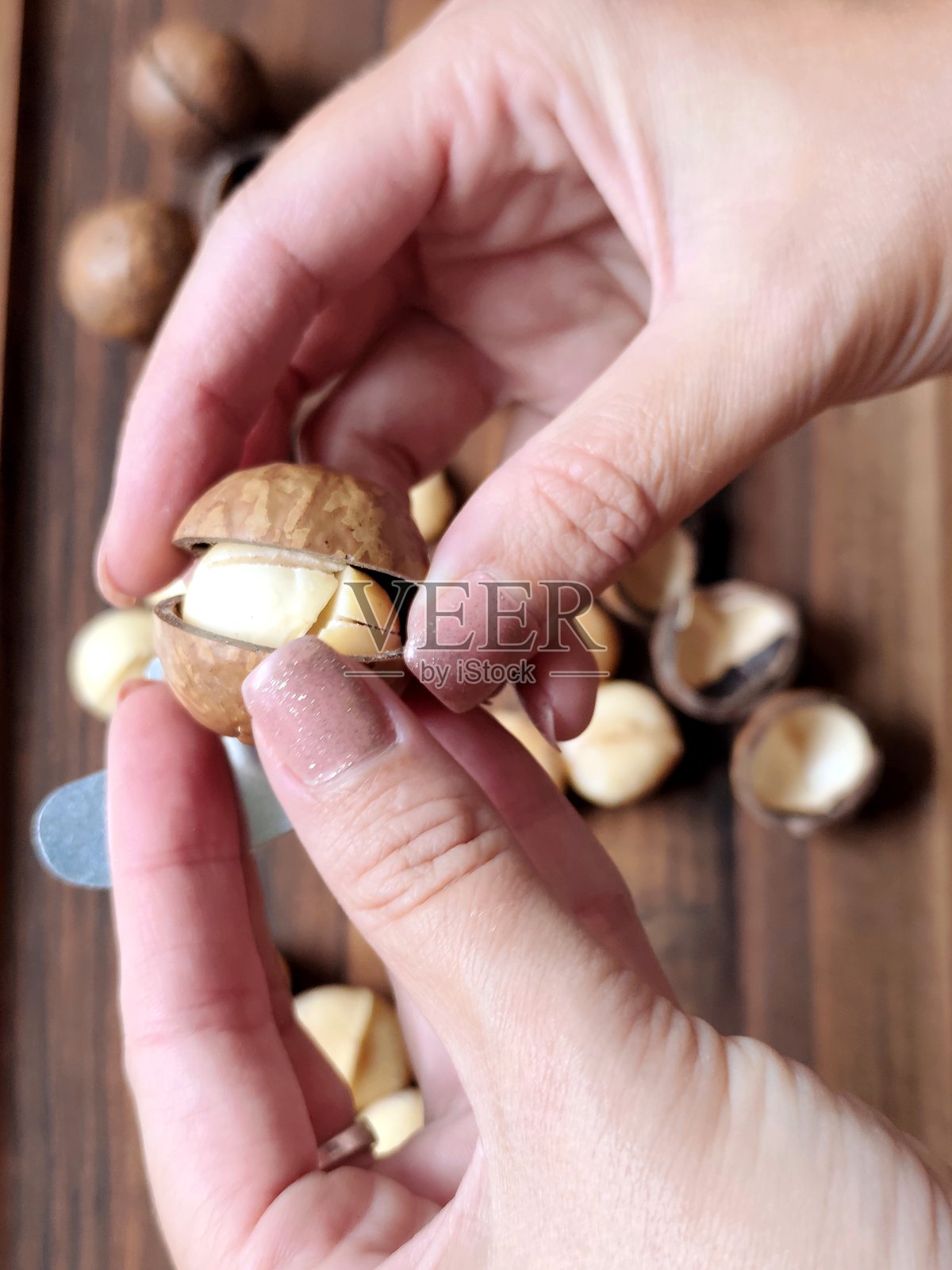 女人用金属钥匙打开夏威夷果照片摄影图片