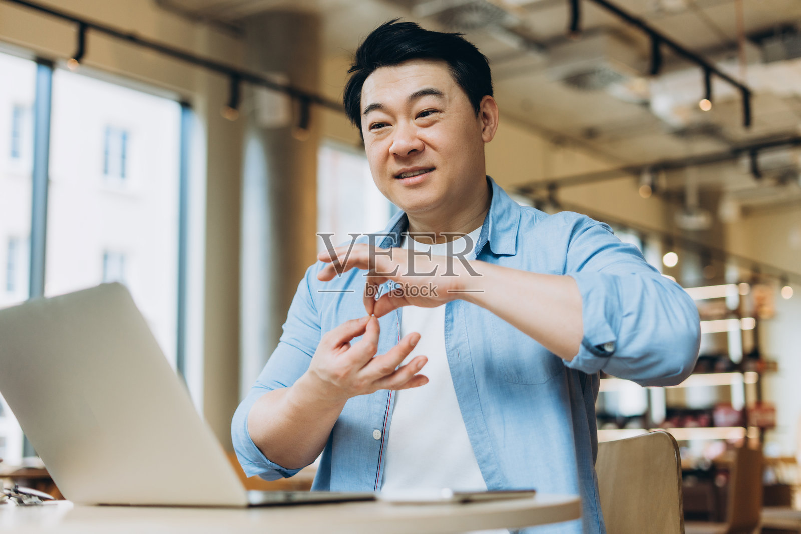 亚洲自由职业者在共享办公空间进行视频通话时做手势照片摄影图片