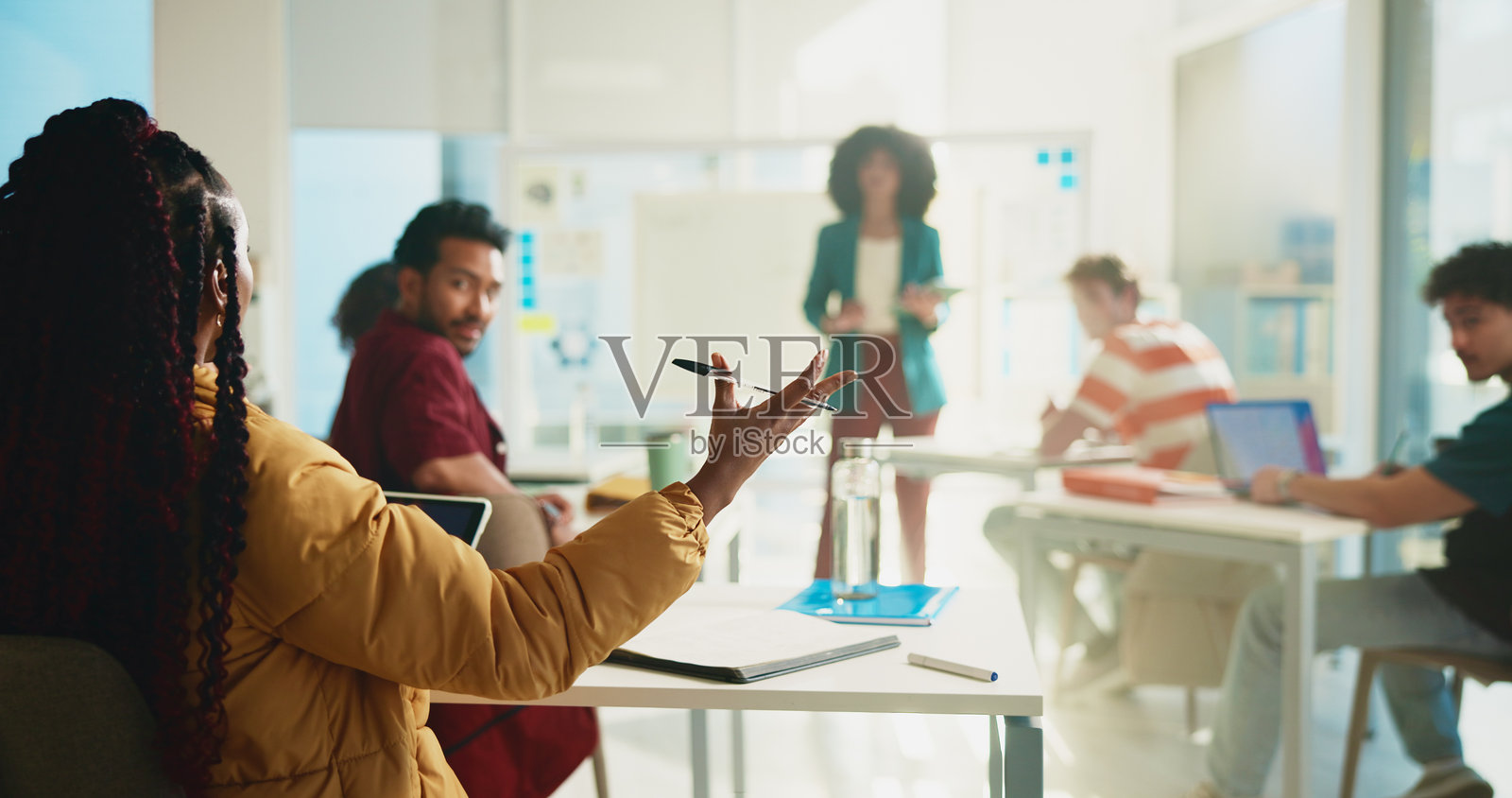 大学课堂上,学生和女性正在讲解学习内容,记录笔记并回答问题。此人背对着观众,正在与奖学金相关的测验进行讨论,手势表达解决方案。照片摄影图片