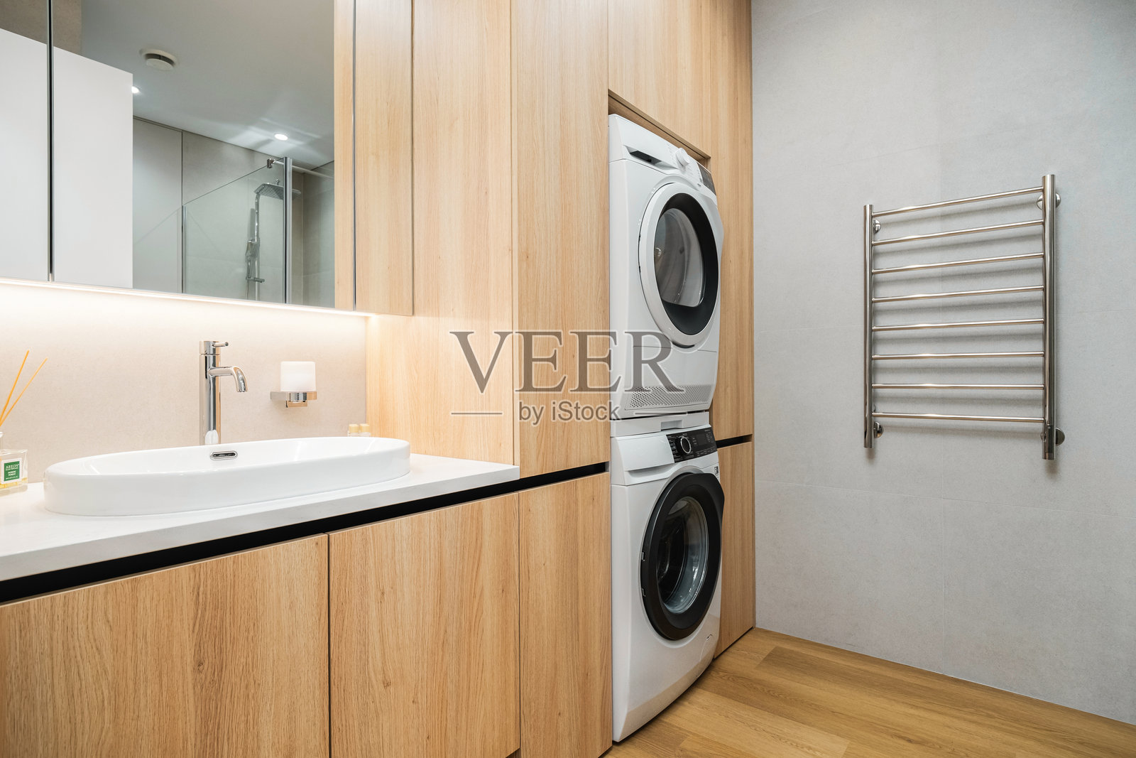 现代洗衣区,配有堆叠式洗衣机和烘干机,采用简约设计,搭配木质橱柜和流畅的饰面。照片摄影图片