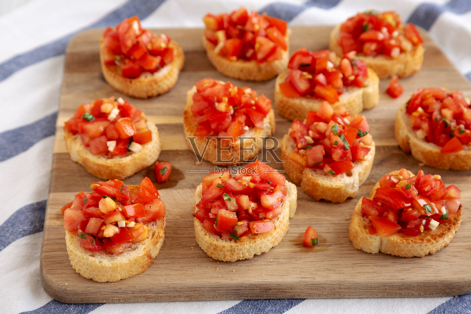 自制意大利开胃菜,配有新鲜罗勒和多汁番茄,摆放在木板上,侧面视图。照片摄影图片